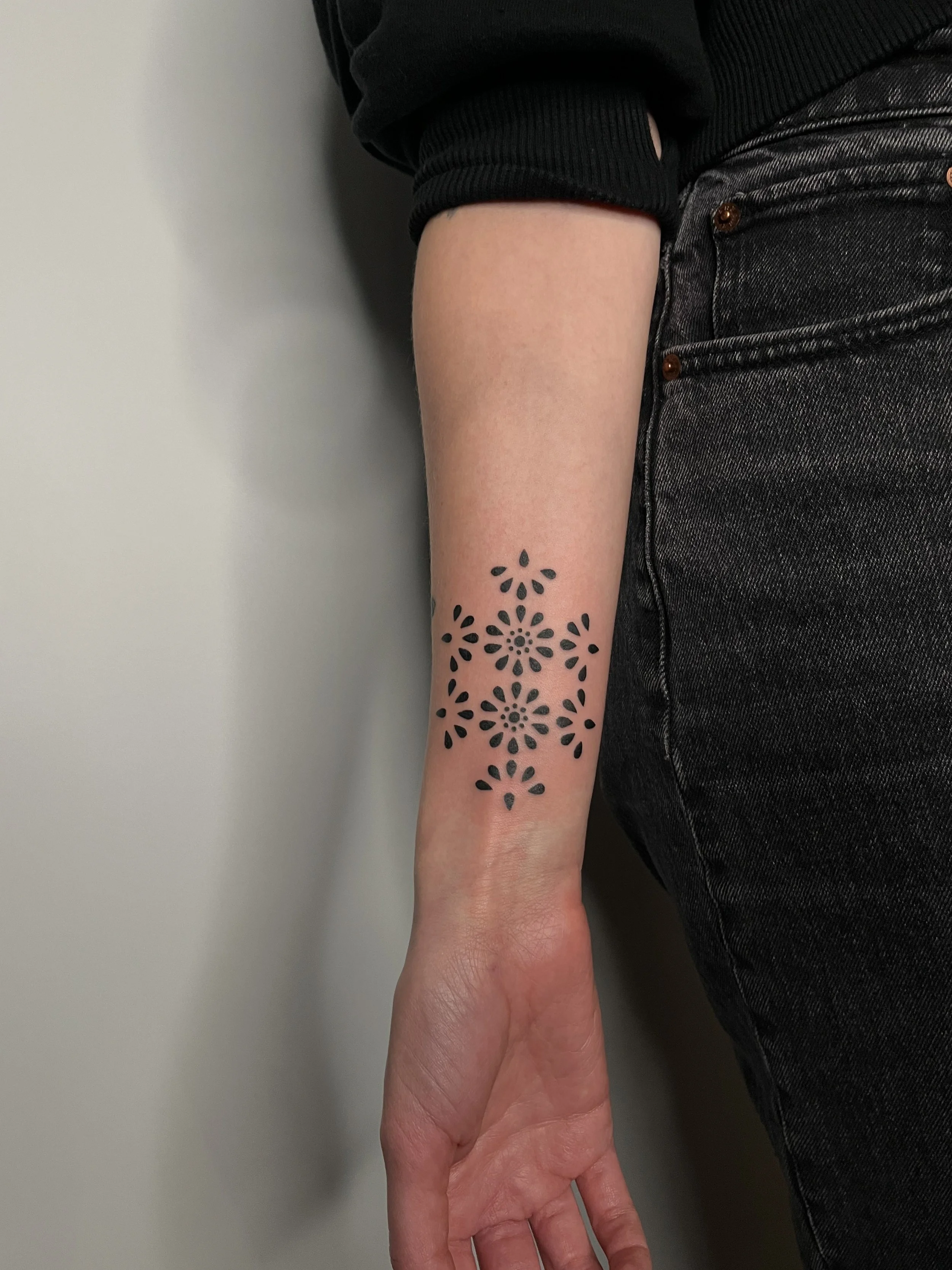Tattoo of black floral patterns on the person's forearm.