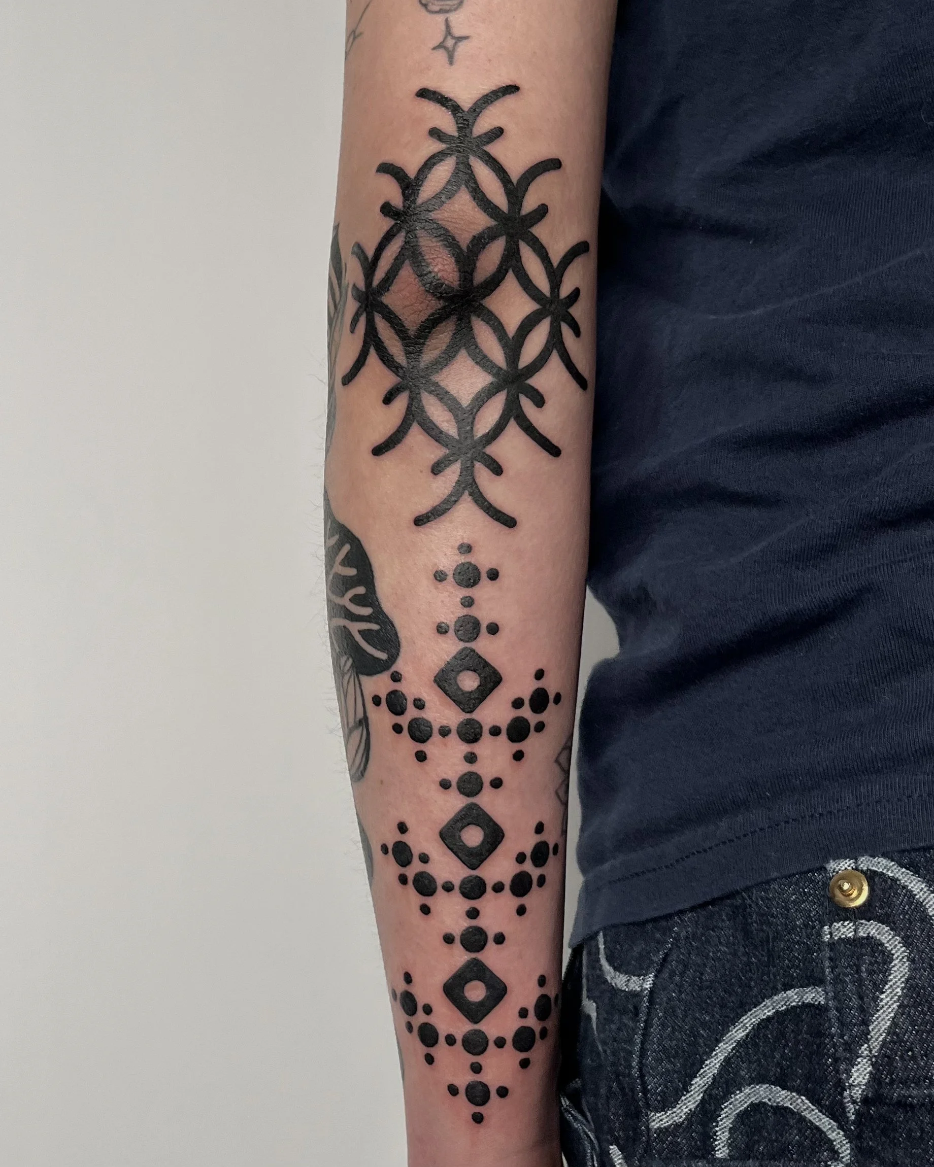 Tattoo sleeve on person's forearm with geometric patterns and black ink designs.