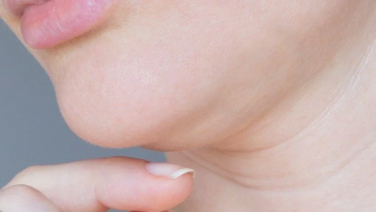 Double Chin - Close-up of a person's chin and lower face with hand gently touching the chin.
