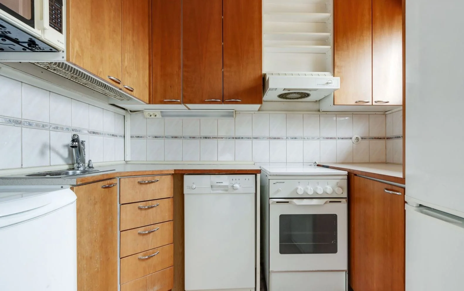 Cuisine avec meubles en bois, évier, gazinière et appareils électroménagers