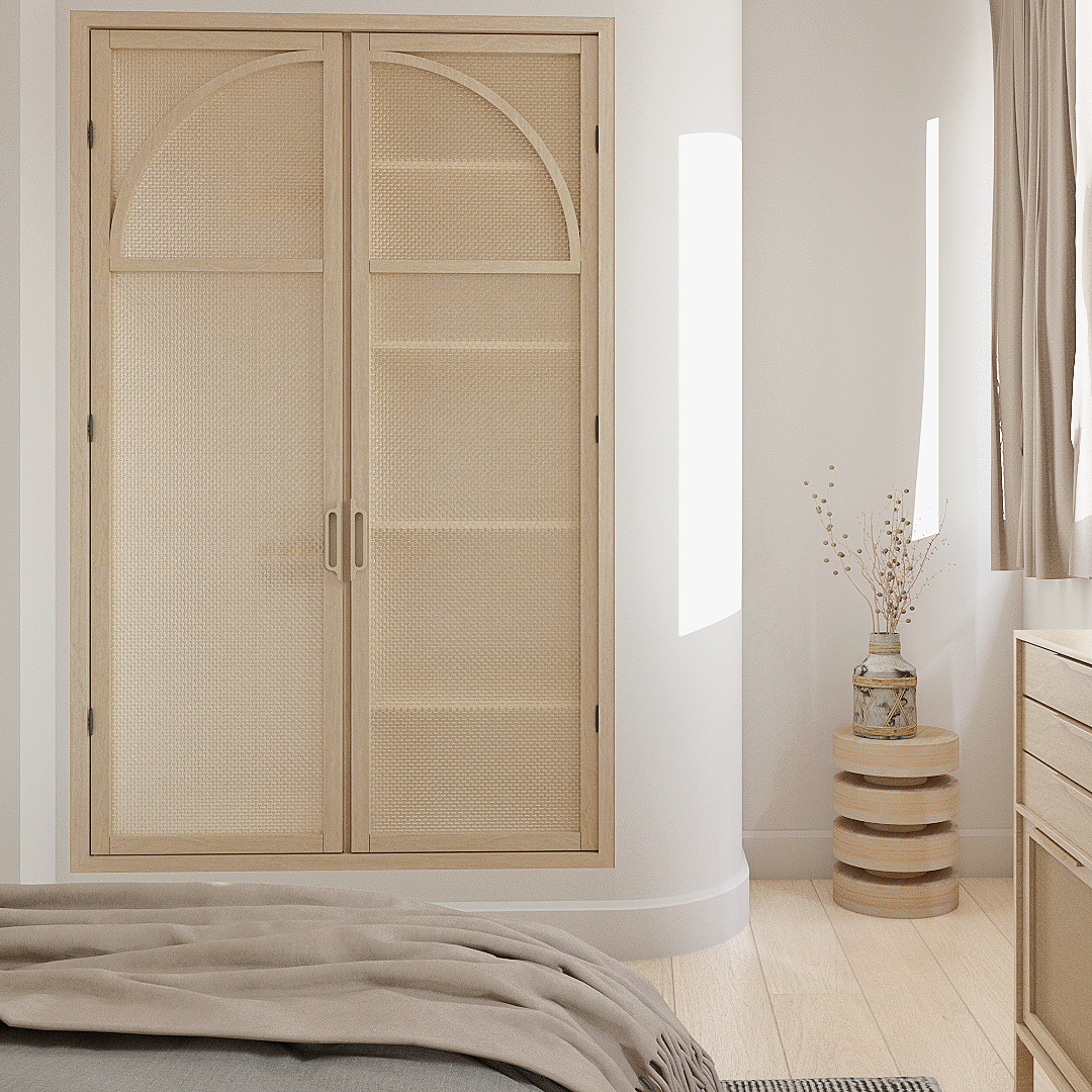 Une armoire en bois clair avec portes en rotin, placé dans un coin d'une chambre. À côté, une petite table en bois avec un vase contenant des branches décoratives.