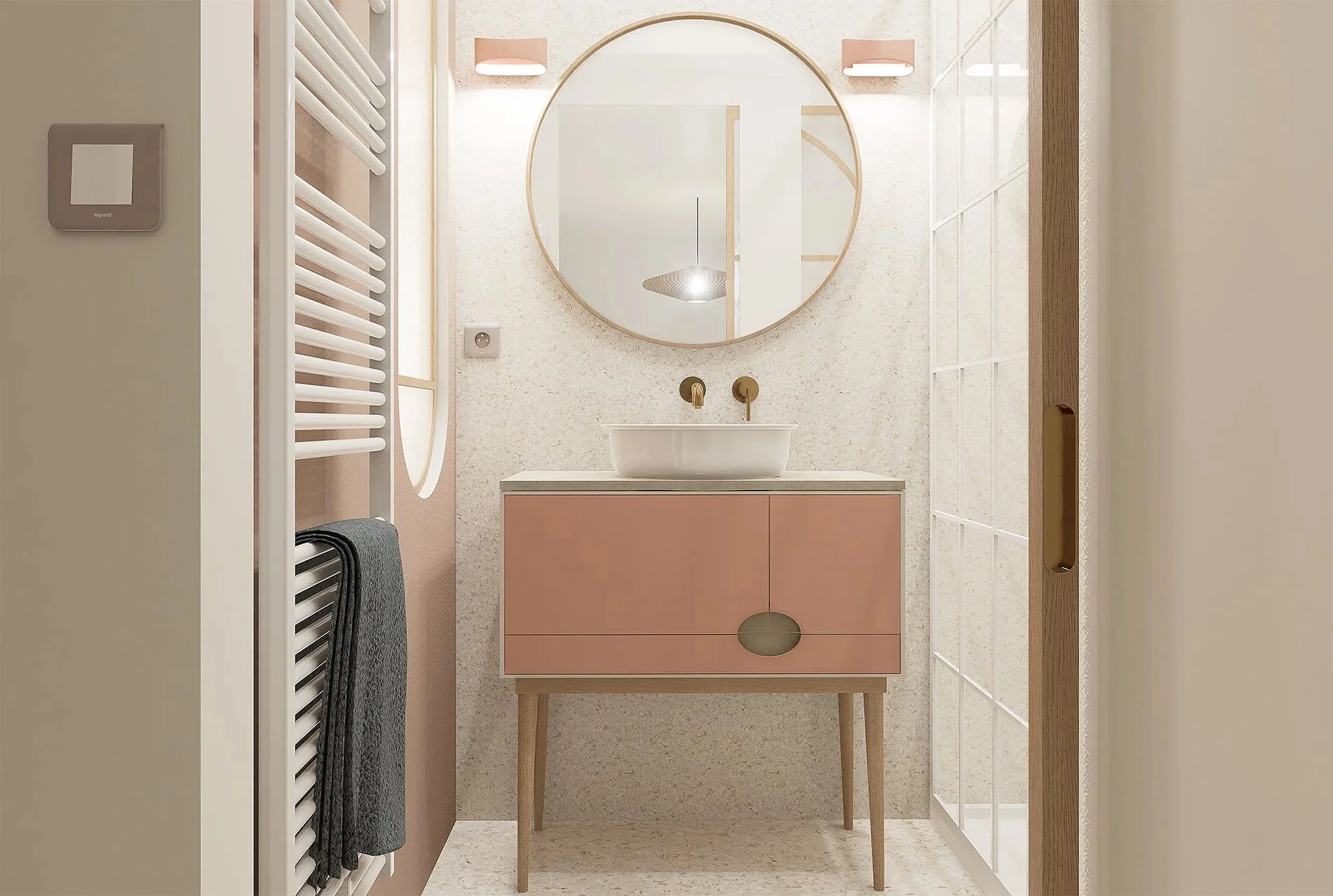 Petite salle de bain moderne avec un miroir rond, vasque blanche sur meuble rose, mur en carrelage clair, porte en bois, radiateur blanc avec serviette noire, et éclairage doux.