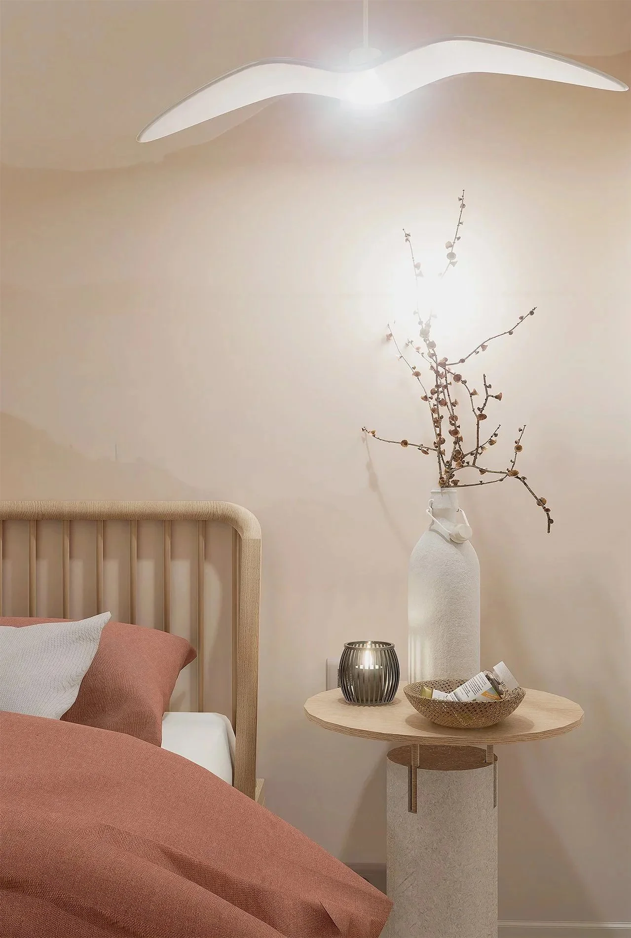 Vue d'une chambre avec un lit en bois, une table de chevet avec un vase contenant des branches sèches, une petite lanterne et une coupelle.