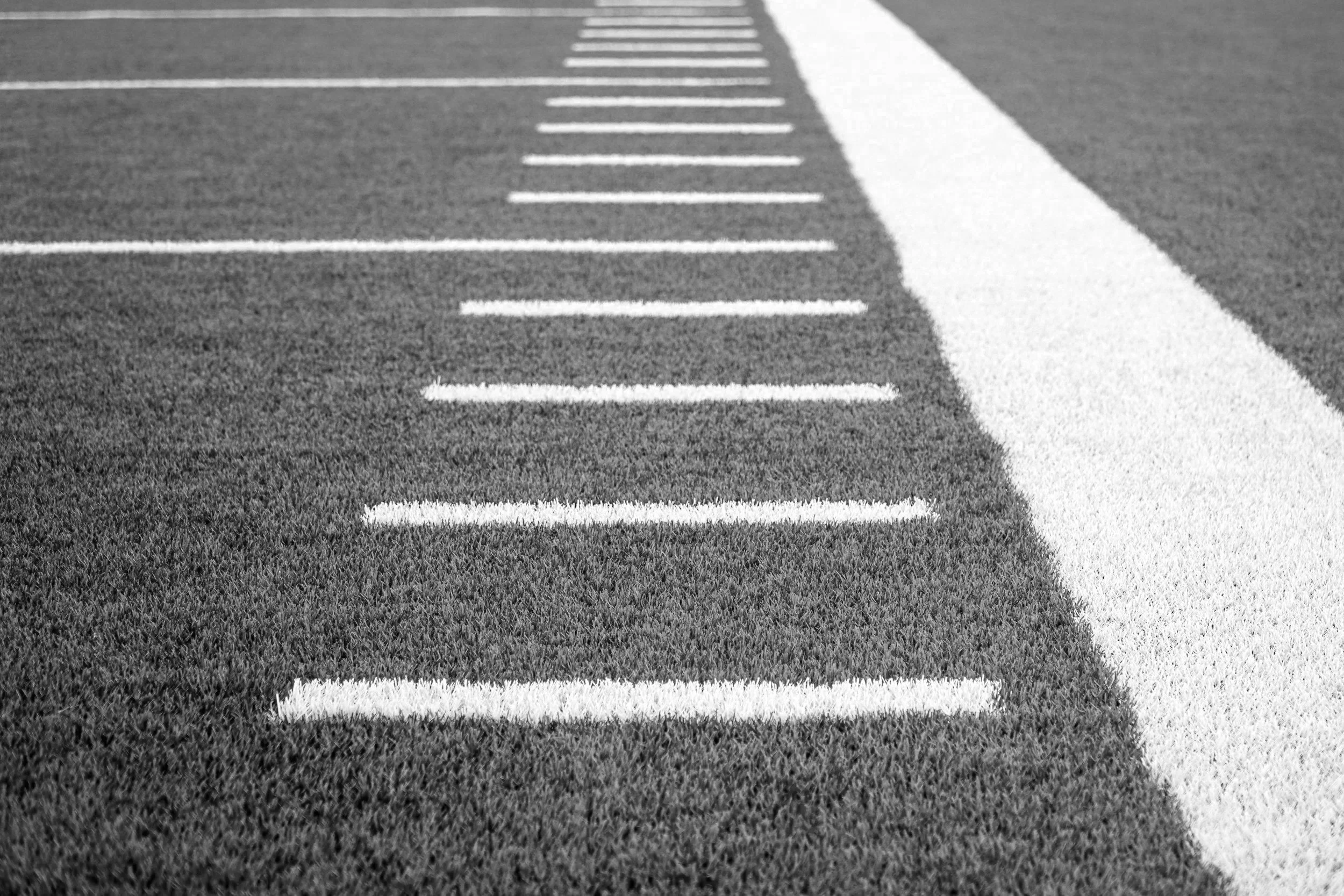 Black and white photograph of a parking lot with painted white lines and a white crosswalk across the asphalt.