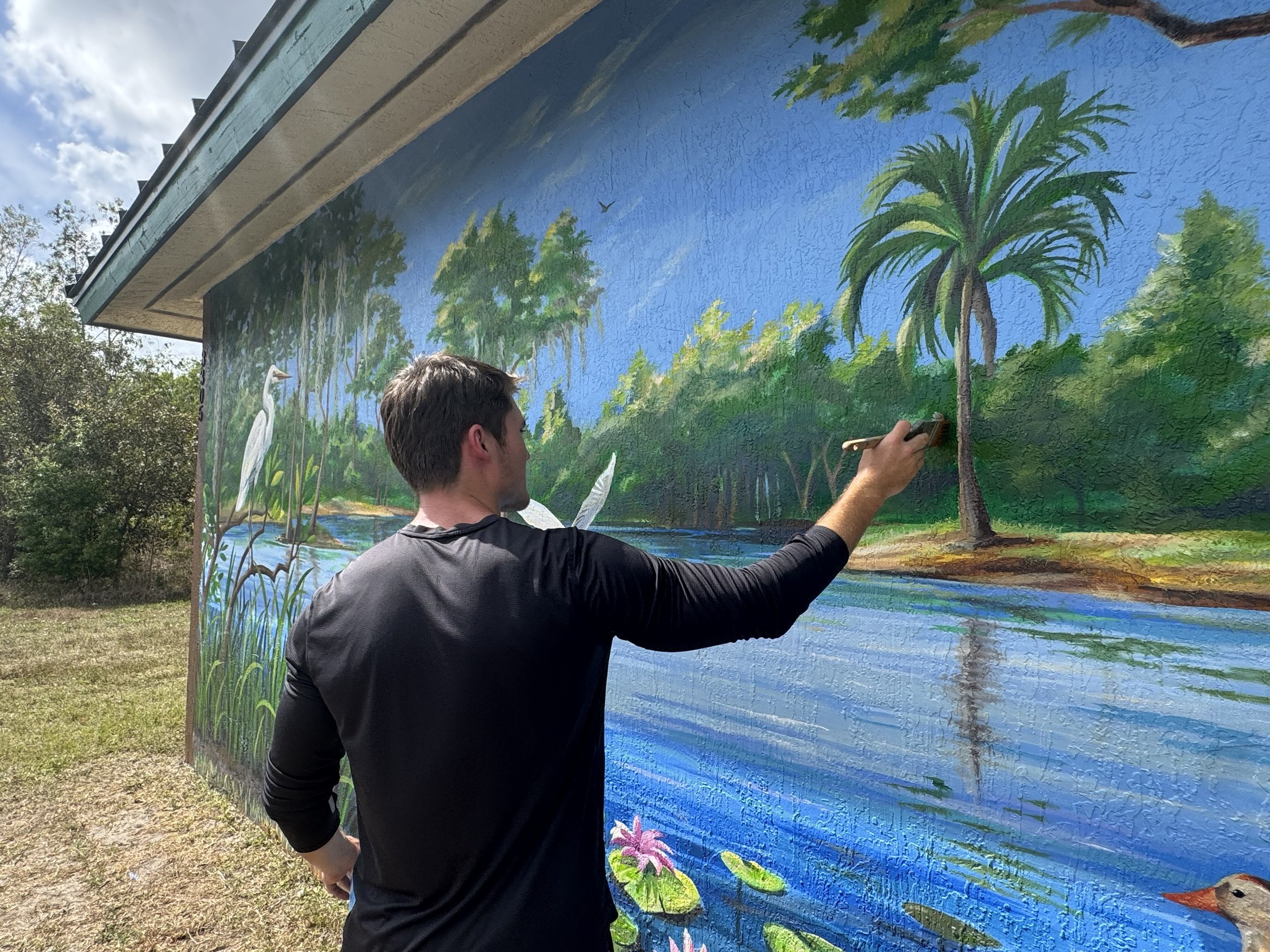 Colin Breslin painting the Song of the Cypress mural