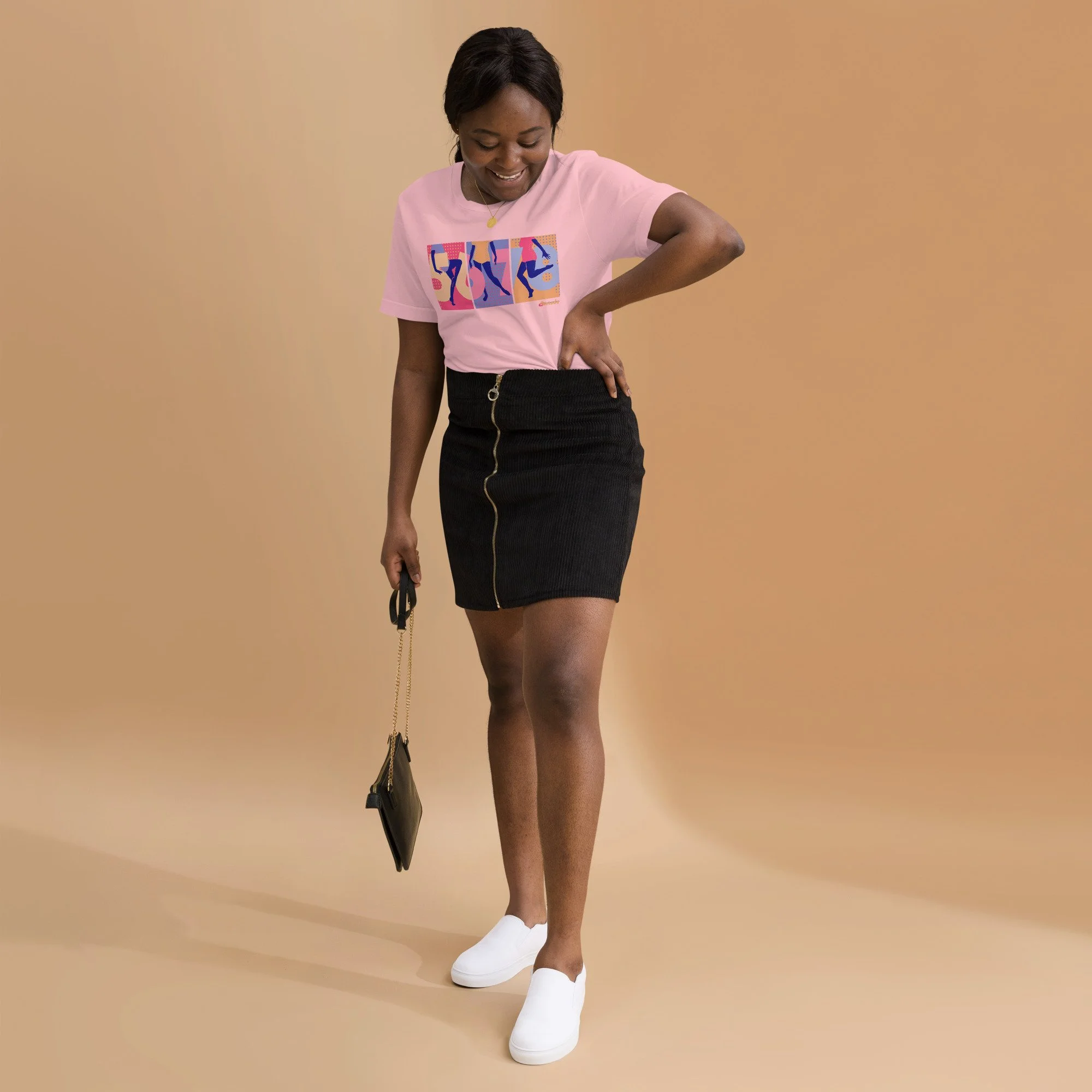 A black woman in her 20s wearing a pink graphic tee with 5,6,7,8 and a dancer in three panels, a demin skirt, and white shoes.