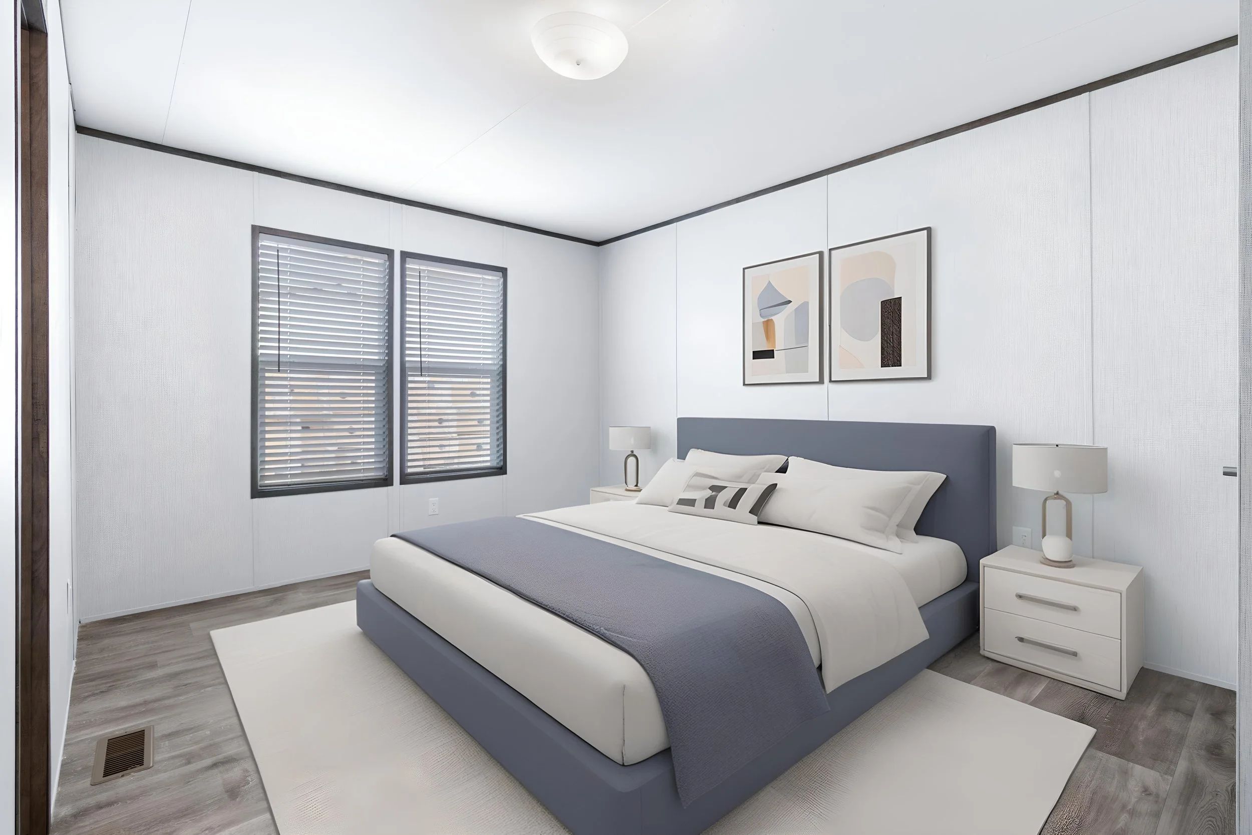 A modern bedroom with a blue bed, white nightstands, abstract artwork, and natural light from two windows with blinds.