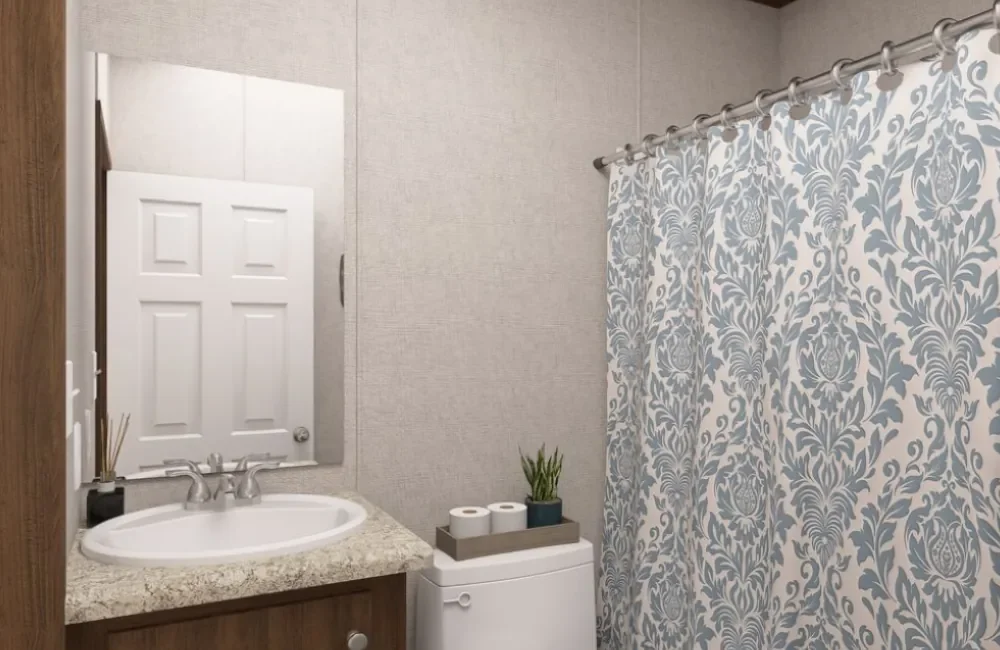 Bathroom with a mirror, sink, countertop, toilet, and shower curtain with a floral pattern.