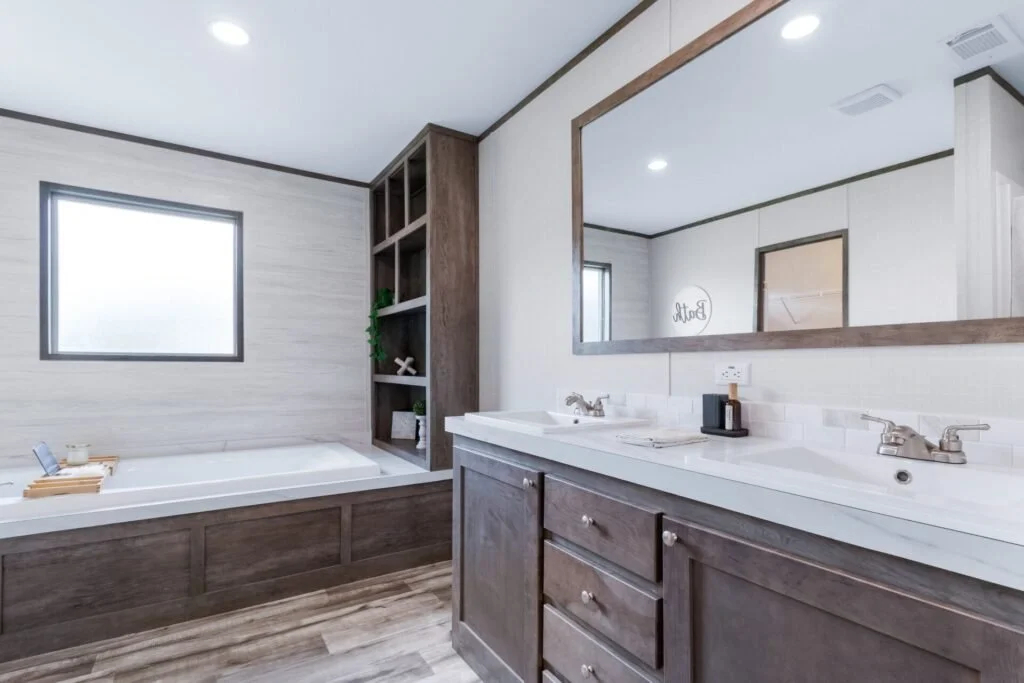 Bathroom with a double vanity mirror, sink, wooden cabinets, a large bathtub, window, and built-in shelves.