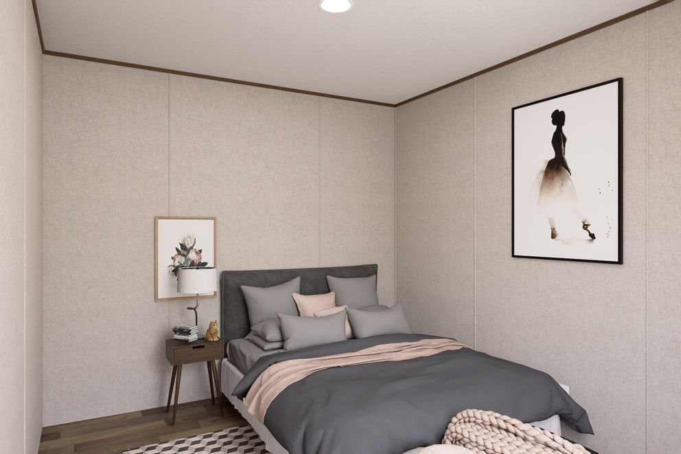 A modern bedroom with a bed, gray and pink bedding, a nightstand with books and a lamp, wall art including floral and fashion illustrations, and hardwood flooring.