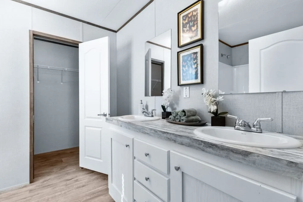 Bathroom with a double sink vanity, counter with towels and flowers, mirror, and framed butterfly artwork.
