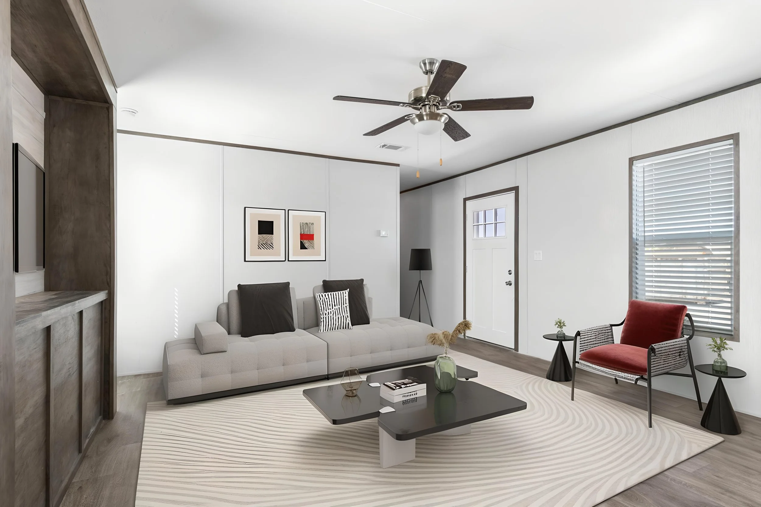 Living room with a beige sofa, black coffee table, red and black chairs, modern artwork, ceiling fan, and large windows with blinds.