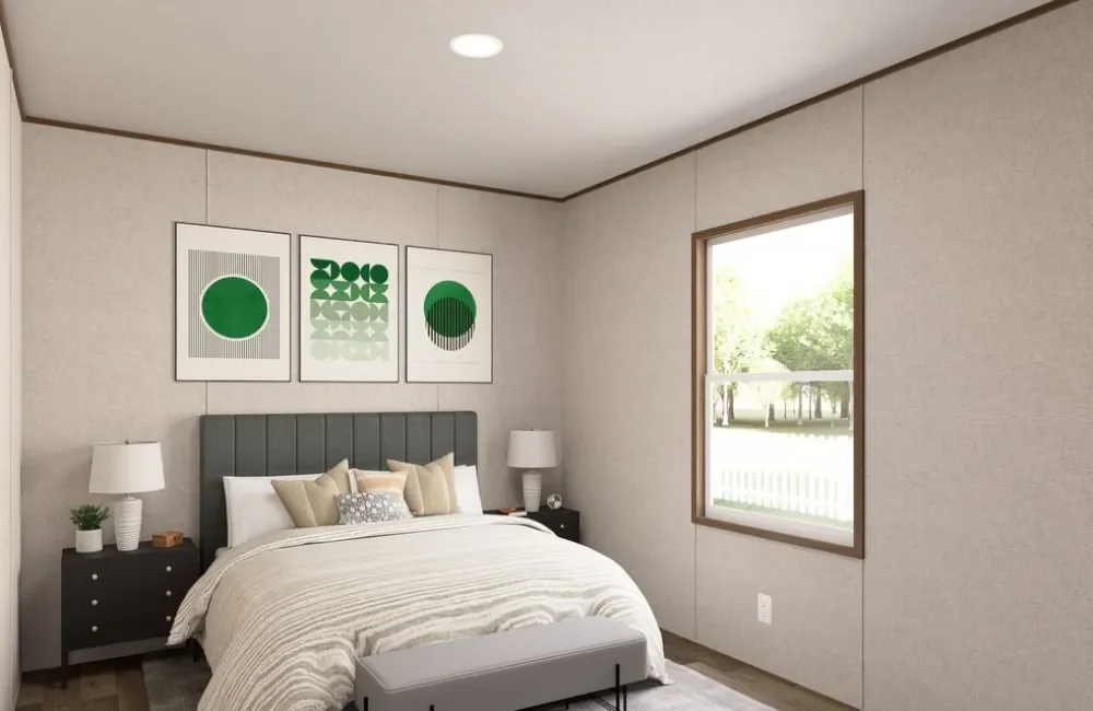 A bedroom with a bed, two nightstands with lamps, and abstract green wall art above the bed. There's a window with a view of trees and grass outside.