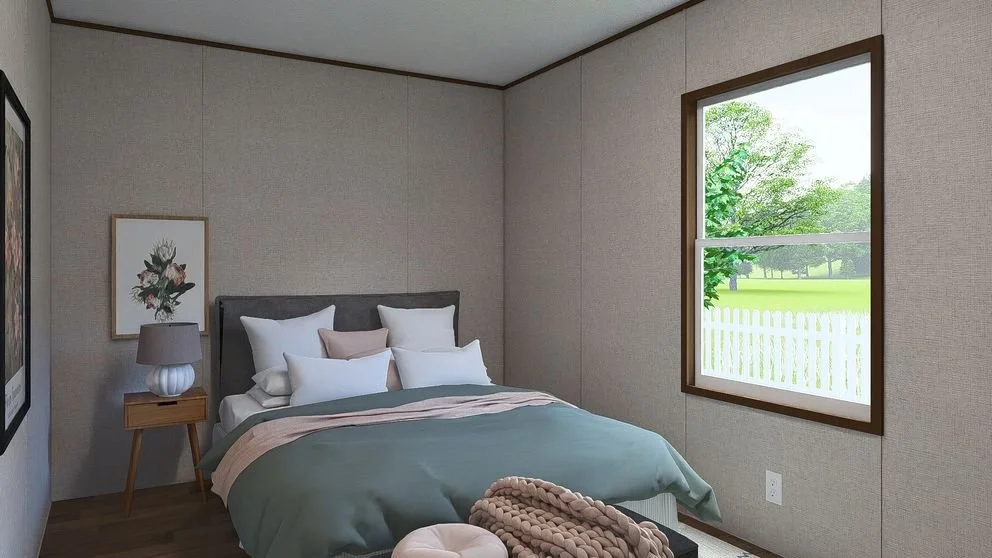 A bedroom with a bed, pillows, blanket, a nightstand with a lamp, framed artwork on the wall, and a window showing a green outdoor scene.