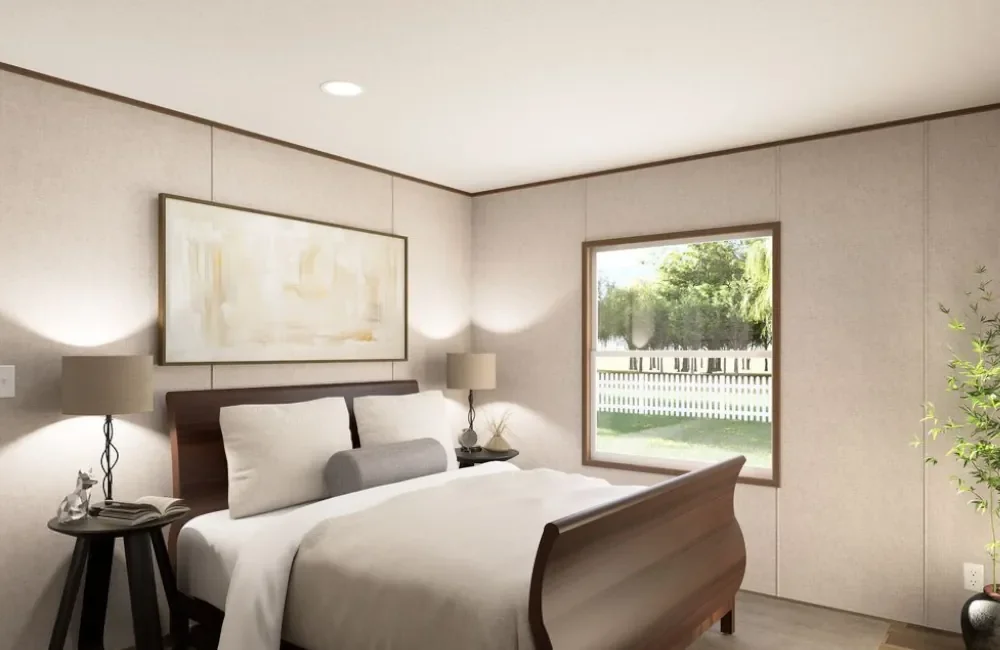 A bedroom with a wooden bed, white bedding, two bedside lamps, a window showing a backyard with a white fence and green trees, and a framed abstract painting above the bed.