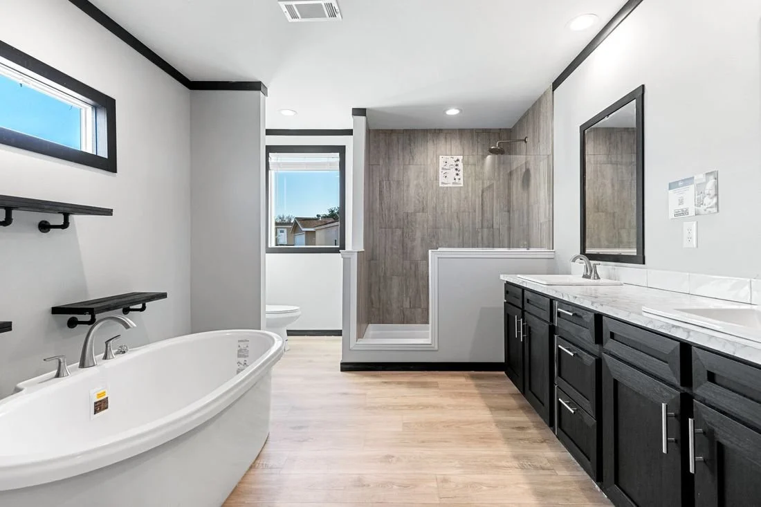 Modern bathroom with a freestanding bathtub, a vanity with a marble countertop, a large mirror, and a walk-in shower with wood accent wall.
