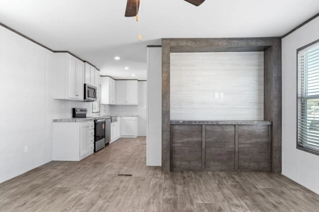 Kitchen with white cabinets, gray countertops, black appliances, and a separate dining area with wood accent wall and window blinds.
