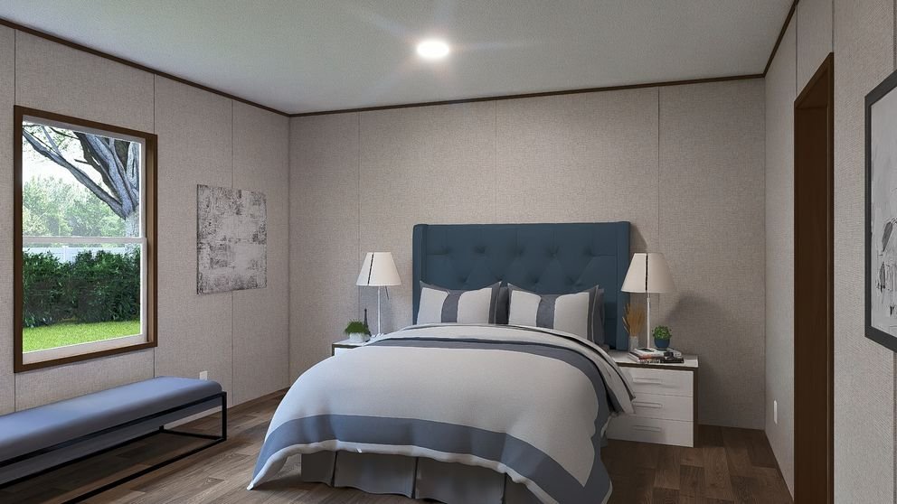 A bedroom with a bed, blue upholstered headboard, grey and white bedding, two nightstands with lamps, a bench near the window, and a picture on the wall.