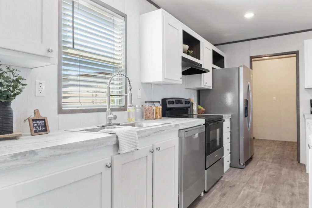 Kitchen with white cabinets, stainless steel appliances, gray flooring, and a window with blinds.