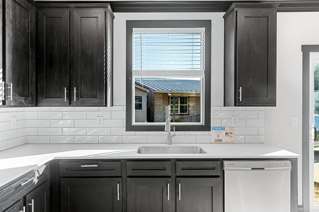 Kitchen with dark cabinets, white countertop, tile backsplash, and window above the sink.