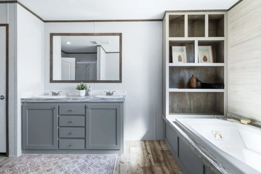 Bathroom with double sink vanity, large mirror, open shelving with decor, and bathtub.