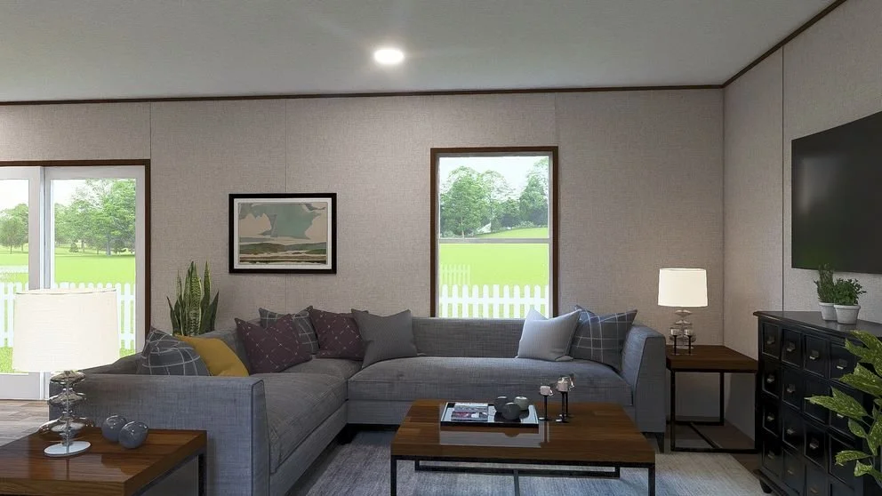 Living room with a gray sectional sofa, throw pillows, a wooden coffee table, side tables with lamps, a black cabinet, a flat-screen TV, and windows showing green grass and trees outside.