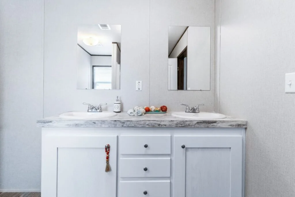 Bathroom vanity with two sinks, a large mirror, soap dispenser, and decorative balls on the countertop.