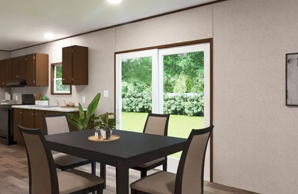 Dining area with a black table, four beige chairs, a potted plant, and a view of green trees through a sliding glass door.