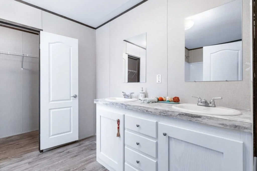 Bathroom with white vanity, double sinks, marble countertop, large mirrors, and open closet with shelving