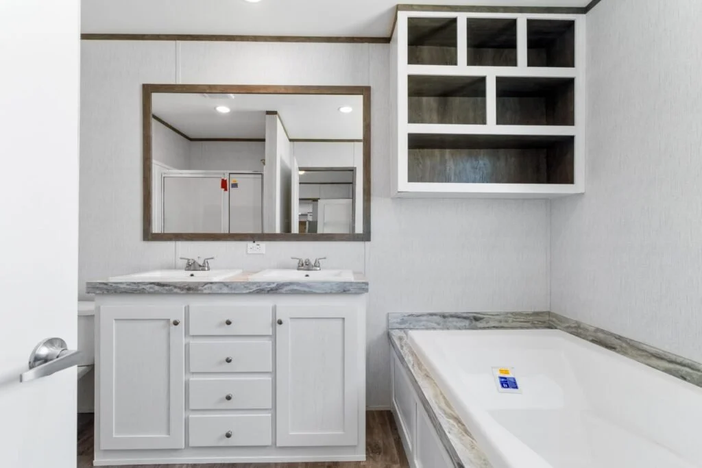 Bathroom with a double vanity sink, a large mirror, open shelves above the bathtub, and a bathtub with a marble surround.