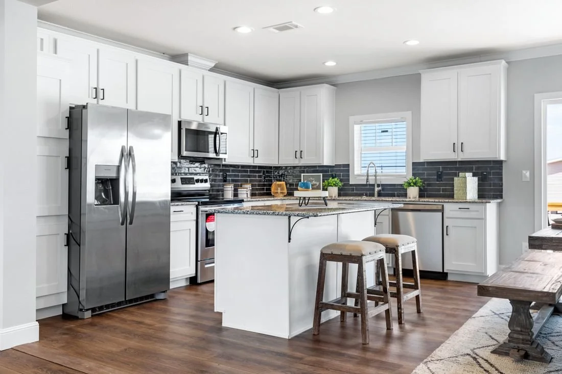 Modern kitchen with white cabinets, stainless steel appliances, black brick backsplash, granite countertops, and wooden flooring.