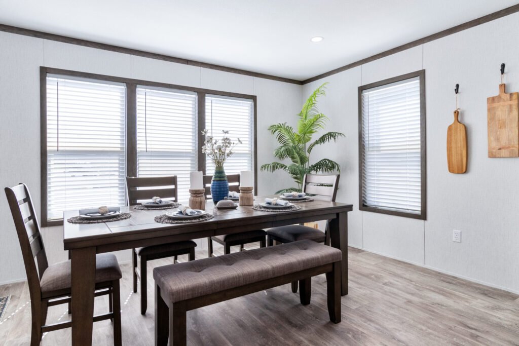 Dining room with a dark wood table, six chairs, a bench, a large potted plant, and windows with blinds.
