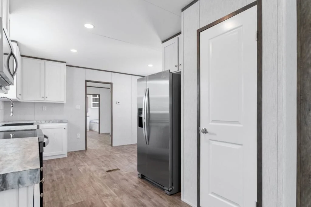 Modern kitchen with white cabinets, stainless steel appliances, and wood flooring.