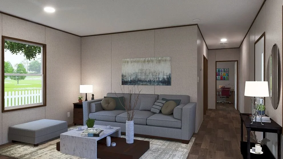 Living room with a grey sofa, an ottoman, a window showing greenery outside, and a hallway leading to a study area.