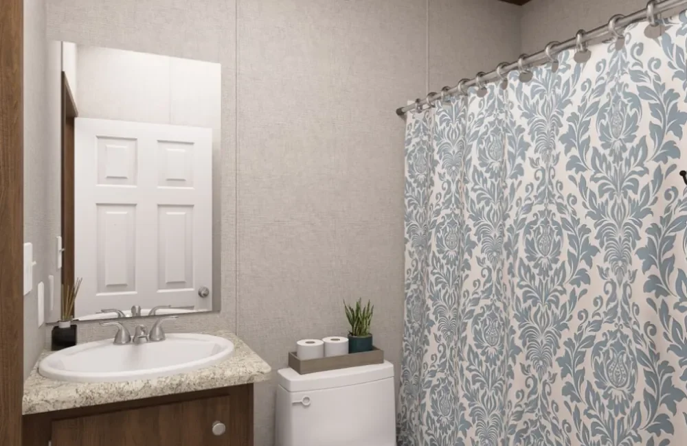 Bathroom with a sink, mirror, toilet, and a shower with a patterned curtain.