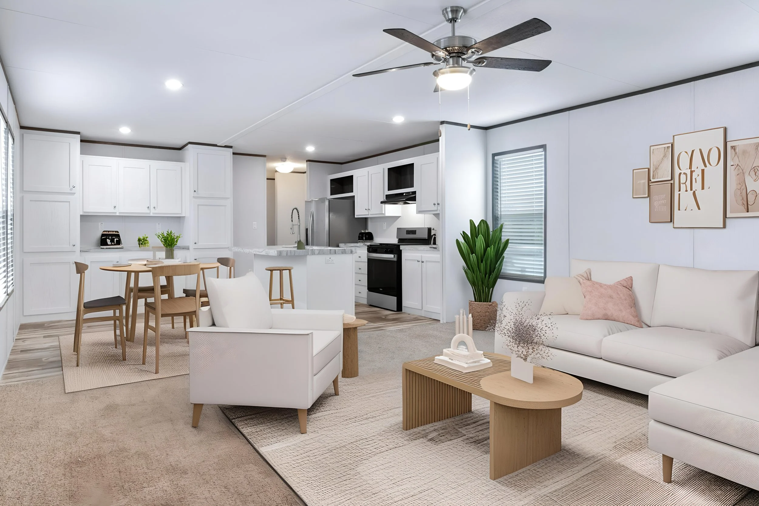 Modern open-concept living room and kitchen with white cabinetry, stainless steel appliances, a ceiling fan, a dining table with chairs, white sofa with cushions, artwork on the wall, and indoor plants.