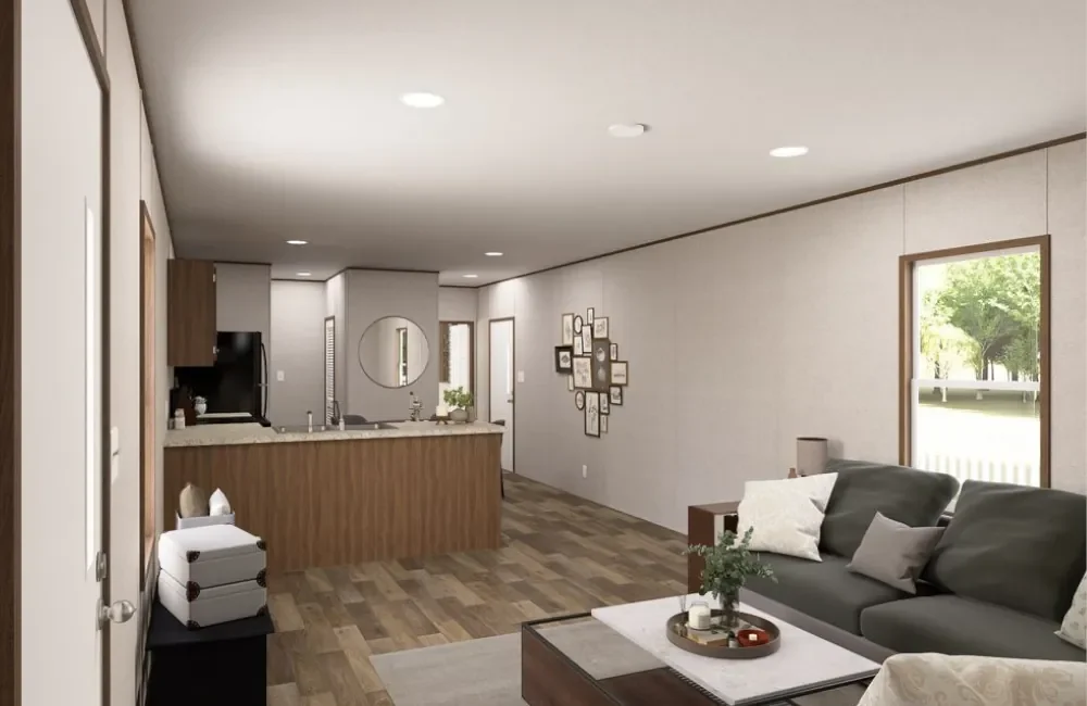 Interior view of a modern living room with a dark sofa, a coffee table, and wall art, with large windows showing a view of a backyard.