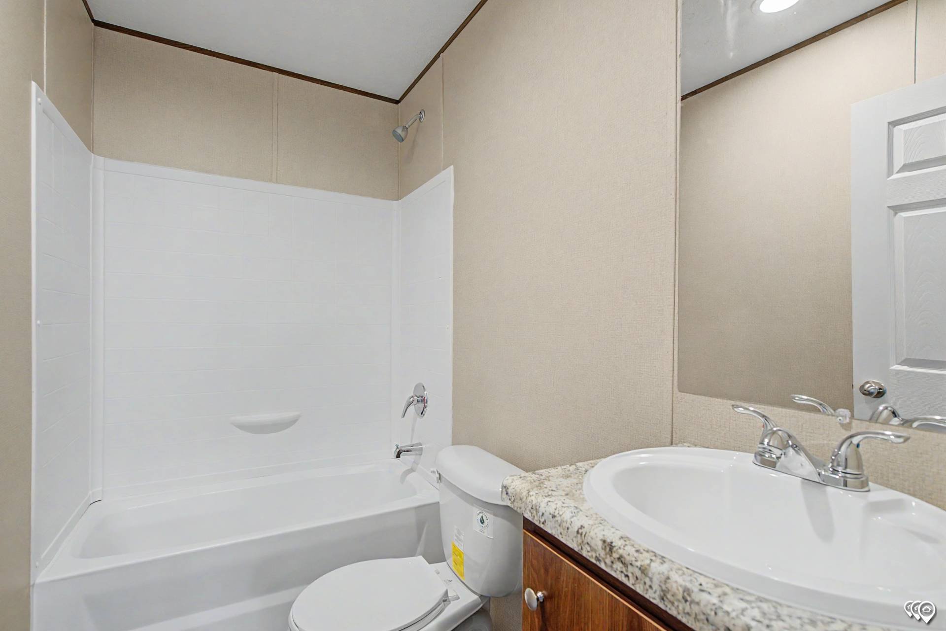 Bathroom with a bathtub and shower, a toilet, a sink with a granite countertop, and mirror.