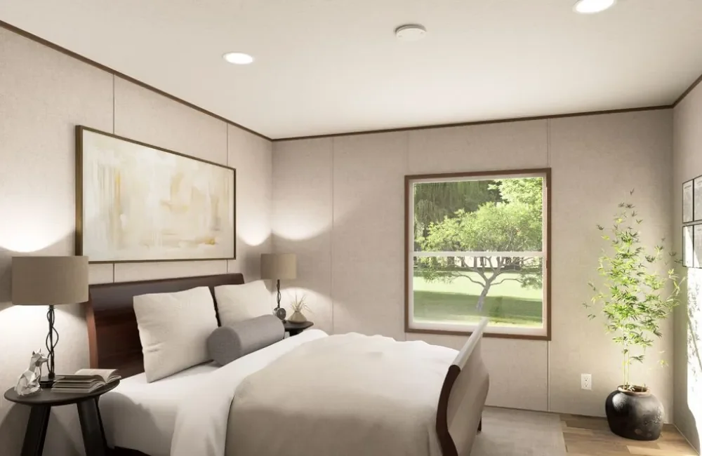 A cozy bedroom with a large bed, two bedside lamps, a window showing green trees outside, a potted plant, and framed pictures on the wall.