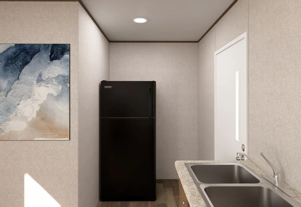 A small kitchen corner with a black refrigerator, a double sink, and an abstract painting on the wall.