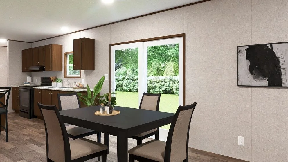 Kitchen and dining area with brown cabinets, black dining table, beige chairs, sliding glass door with view of green yard, and abstract black and white wall art.