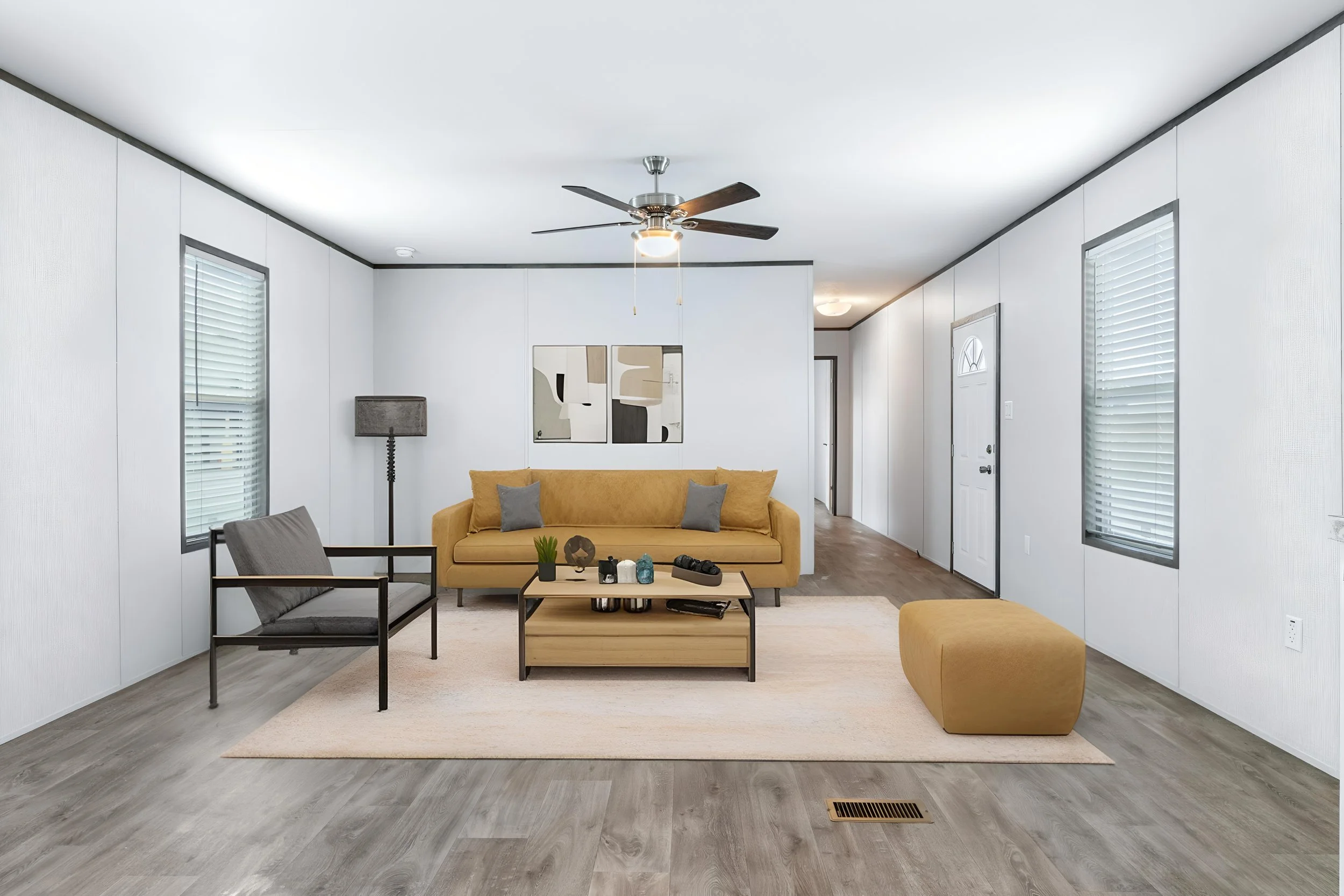 Living room with yellow couch, black armchair, coffee table, white walls, windows with blinds, ceiling fan, abstract wall art, and hardwood flooring.