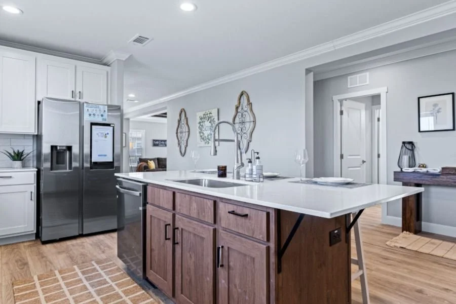 Modern kitchen with white cabinets, a stainless steel refrigerator, a wooden kitchen island, and decorative wall art.