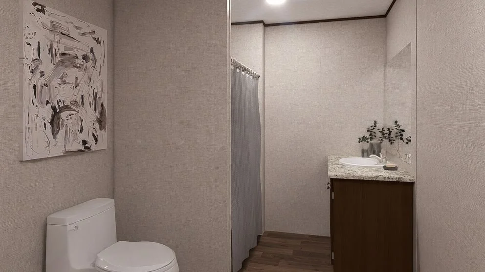 A small bathroom with a toilet, a shower with a curtain, and a vanity with a sink and a decorative plant.