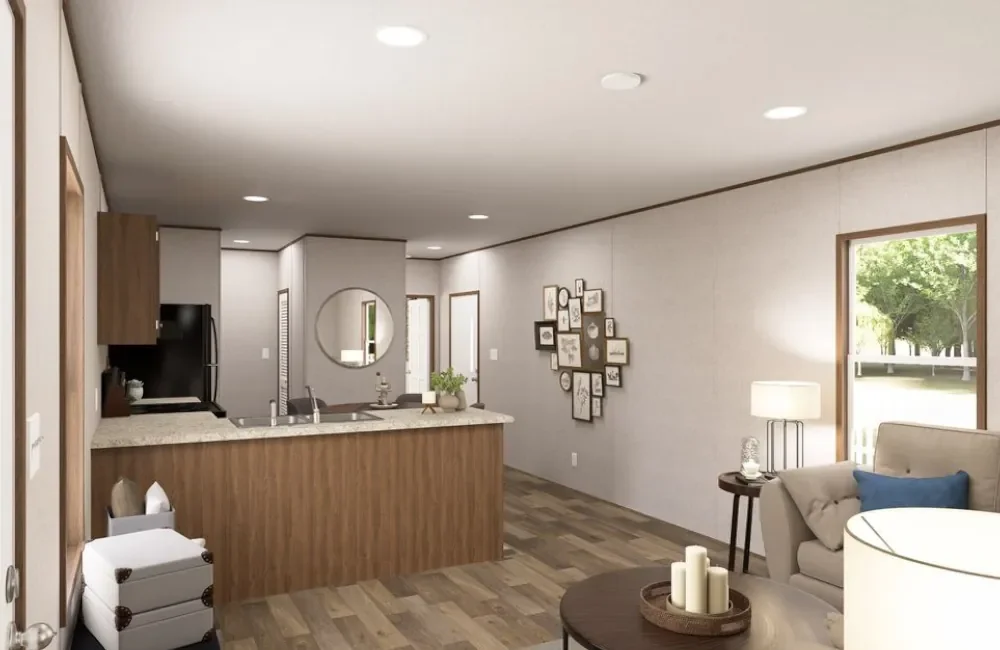 Open-concept living room and kitchen in a modern home with wood accents, framed pictures on the wall, a sofa with throw pillows, a side table with a lamp, and a window with outdoor greenery.