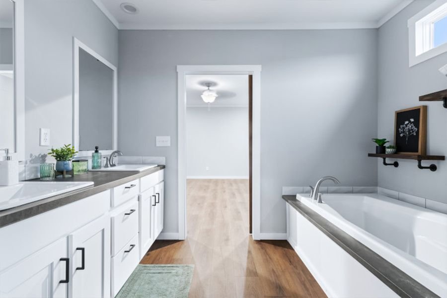 Bathroom with double sink vanity, bathtub, and wooden shelves with decorative items