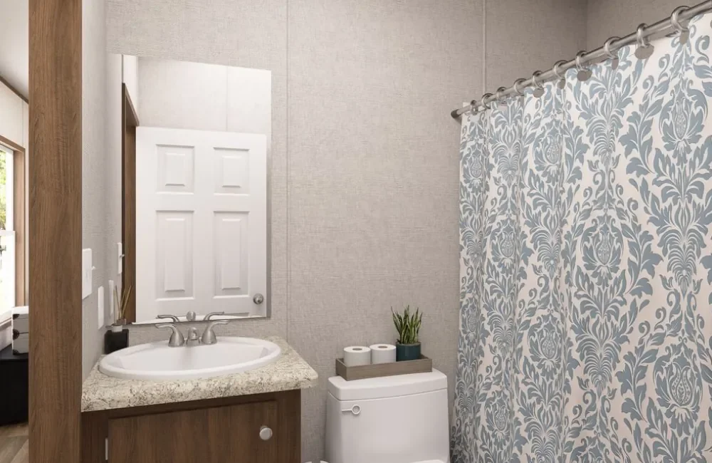 Bathroom with sink, mirror, toilet, decorative shower curtain, and a small plant.