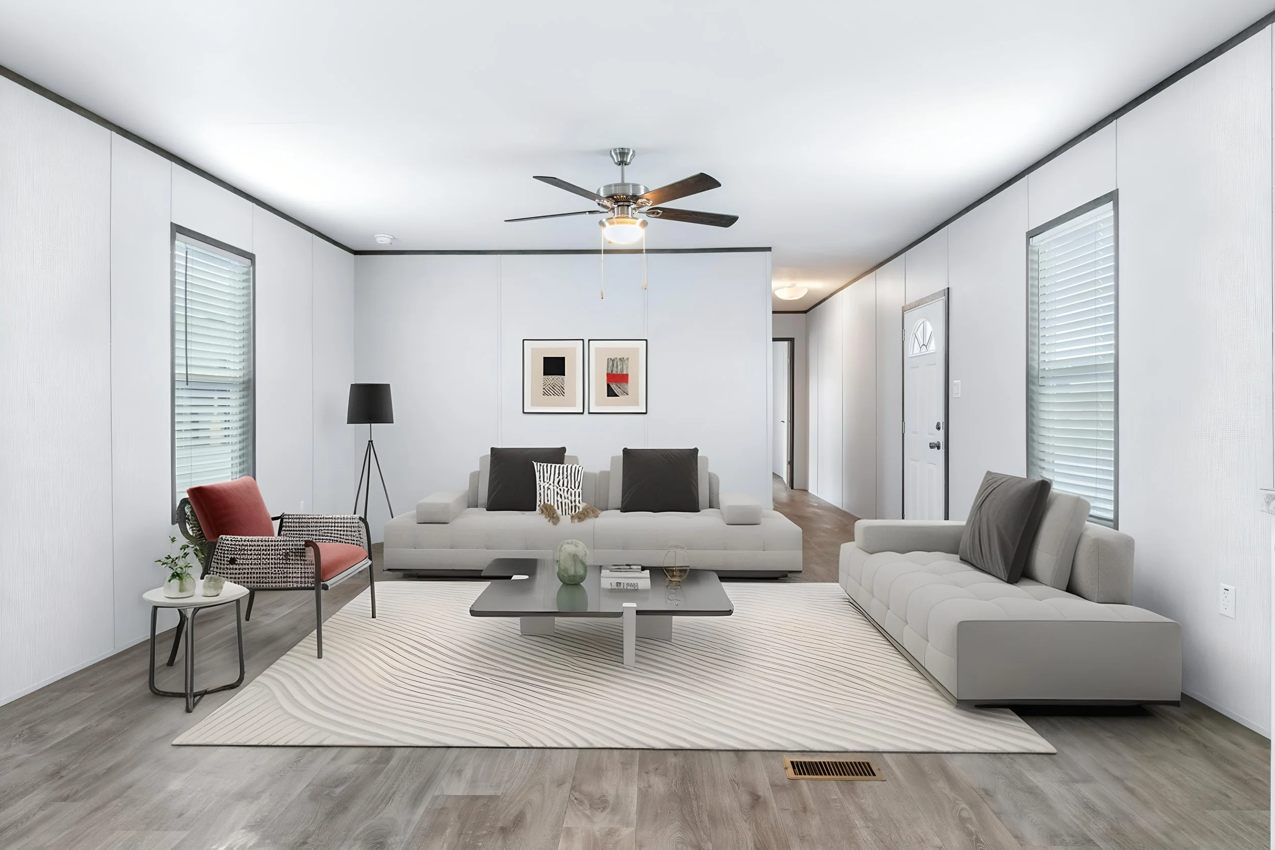 Living room with white walls, grey flooring, and modern furniture including a white sofa, grey armchair, black lamp, and coffee table, decorated with framed art and plants.