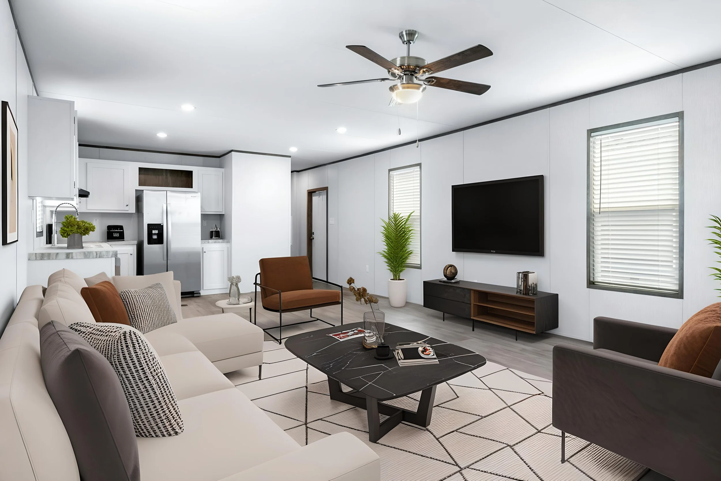 Living room with white patterned tile floor, beige sofa with black and white pillows, brown armchair, black coffee table, black TV on white wall, large potted plant, kitchen visible in background, ceiling fan, windows with blinds.