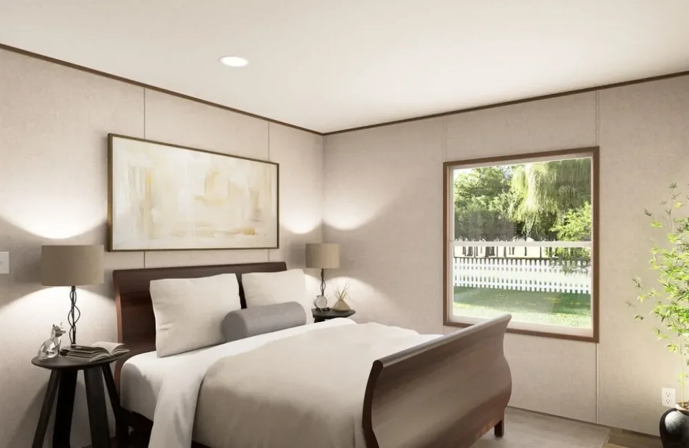 A bedroom with a wooden bed, white bedding, two lamps on bedside tables, a window showing a white fence and green trees outside, and a potted plant in the corner.